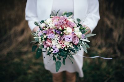 Midsection of woman holding bouquet of flowers