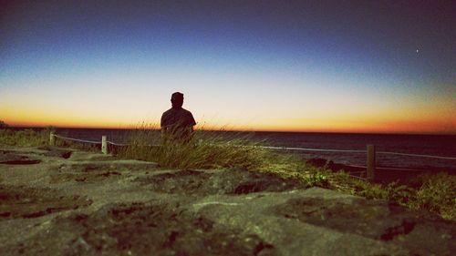 Rear view of man on beach against clear sky