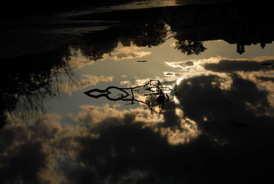 Silhouette tree by lake against sky during sunset