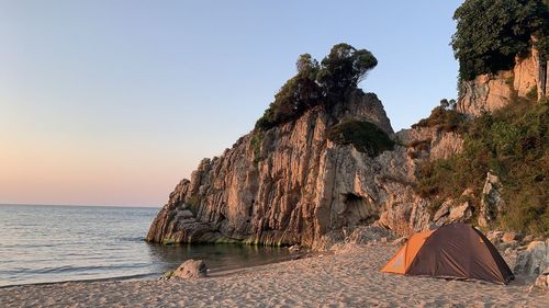 Rock formations on shore by sea against clear sky