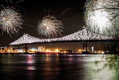 Firework display over river against sky at night