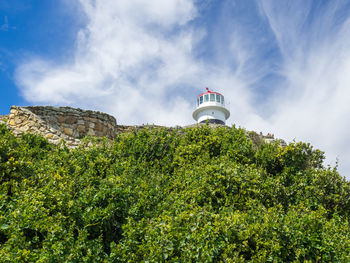 Low angle view of historical lighthouse at cape point building against cloudy sky, south africa