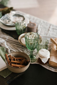 Festive christmas table setting. green glass glasses and cinnamon sticks in a clay plate