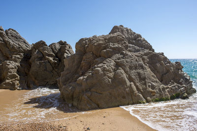 Rock formation on beach against clear sky