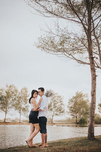 Full length of couple standing by trees against sky