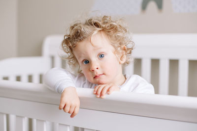 Cute adorable baby boy toddler standing in crib at kids nursery room at home. curious charming baby 