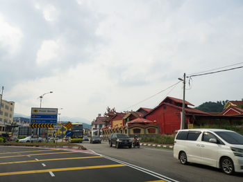 Cars on road by buildings against sky