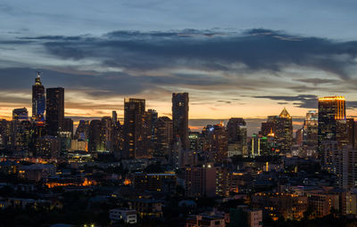 Illuminated buildings in city against sky during sunset