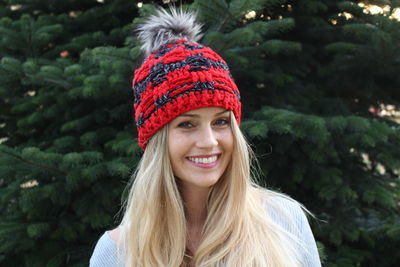 Portrait of smiling young woman wearing warm clothing against plant