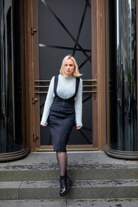 Full length portrait of woman standing on doorsteps