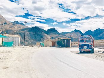 Scenic view of road by mountains against sky