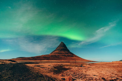 Scenic view of arid landscape against aurora borealis