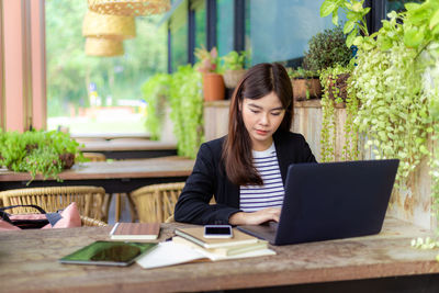 Young woman using mobile phone while sitting on table