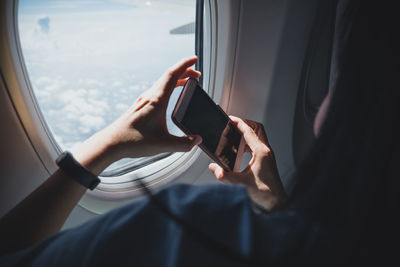 Midsection of man using mobile phone in airplane