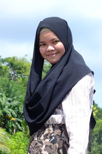 Portrait of smiling teenage girl in headscarf while standing outdoors