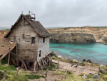 Built structure on shore by houses against sky