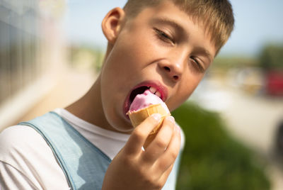 The boy is eating ice cream. pink strawberry ice cream in a waffle cup. enjoyment. yummy ice-cream.