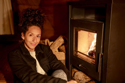 Joyful and relaxed woman sitting next to fireplace.