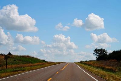 Road amidst field against sky