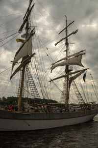 Boats in sea against cloudy sky