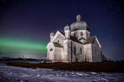 Church on field against sky at night during winter