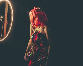 Full length of girl standing against illuminated wall