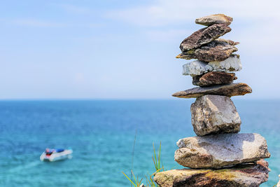 Stack of rocks by sea against sky