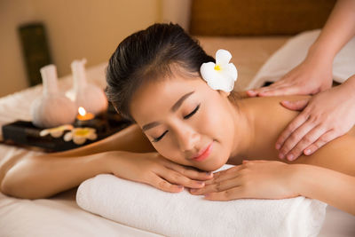 Cropped hands giving massage to young woman lying on bed in spa