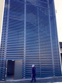 Rear view of woman walking against building in city