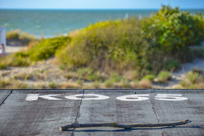 Arrow sign on road by sea