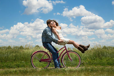 Man riding bicycle on field against sky