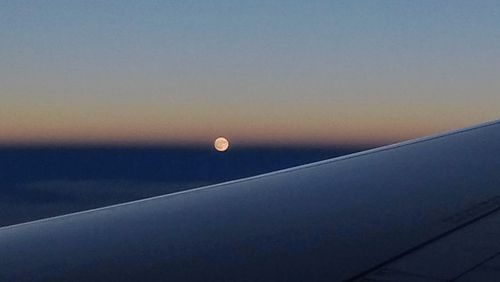 Airplane wing against sky during sunset