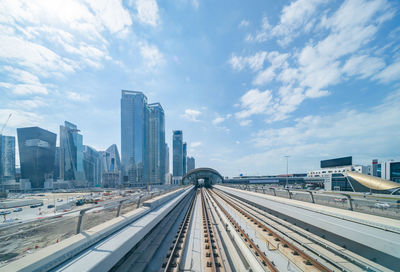 Railroad tracks amidst buildings in city against sky