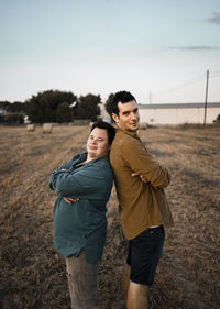 Male friends with arms crossed standing back to back