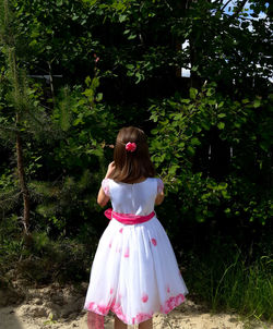 Rear view of woman standing against trees