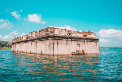 Built structure in sea against cloudy sky