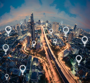 Aerial view of illuminated cityscape with connecting dots against sky