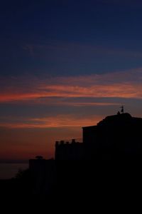 Silhouette of building against sunset sky