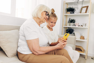 Young woman using mobile phone while sitting on sofa at home