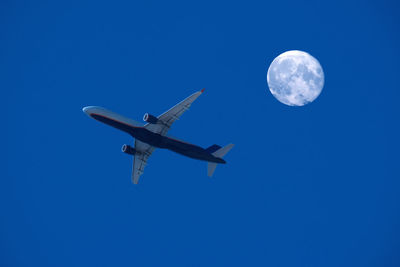 Low angle view of airplane against clear blue sky