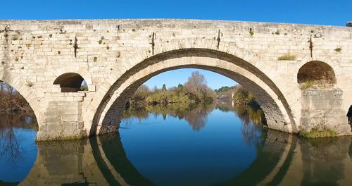 Arch bridge over river against sky