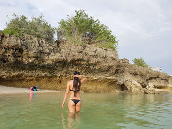 Rear view of women on rock against sky