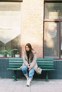 Full length portrait of woman sitting on seat
