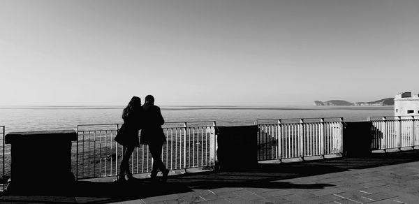 Rear view of people looking at sea against sky