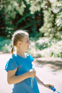 Side view of girl blowing bubbles in park