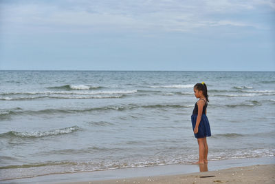 Full length of woman standing on beach against sky