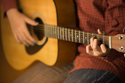 Midsection of man playing guitar