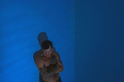 Young man standing against blue background