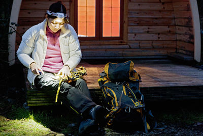 Woman sharpening her crampons in front of camping pod in the uk