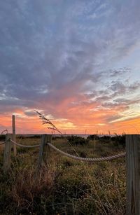 Fence on field against sky during sunset